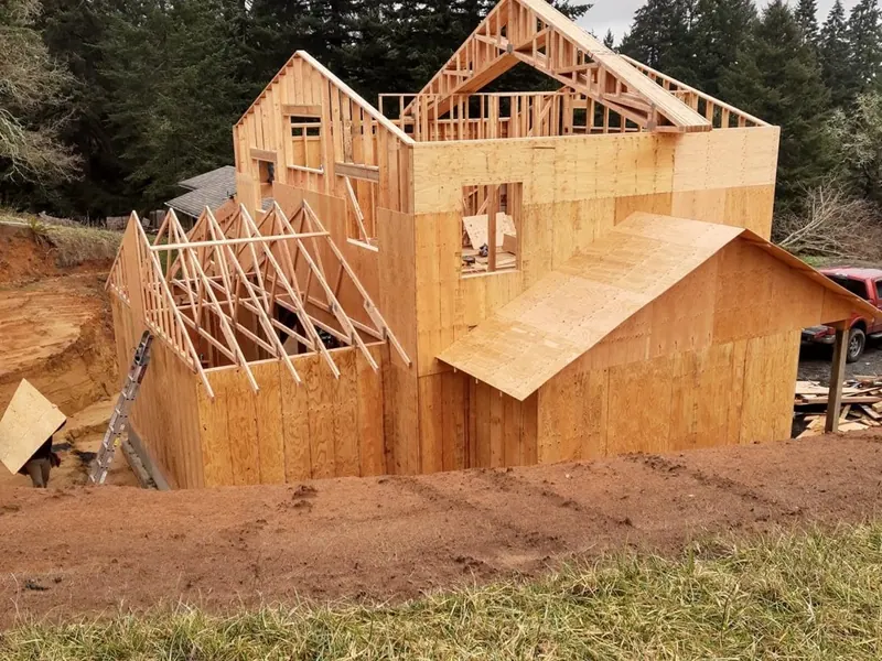 OSB-sheathed two-story framing of a new garage and ADU nearing wall-completion during Pacific Northwest winter.