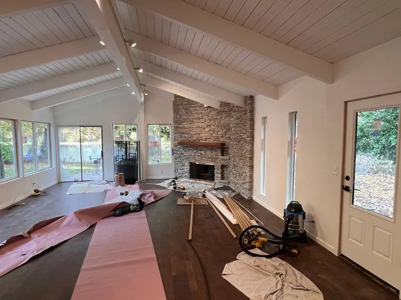 Stunning open-concept living room remodel with white shiplap vaulted ceiling, exposed beams, and stacked-stone fireplace built in Eugene, Oregon by Red Umbrella.