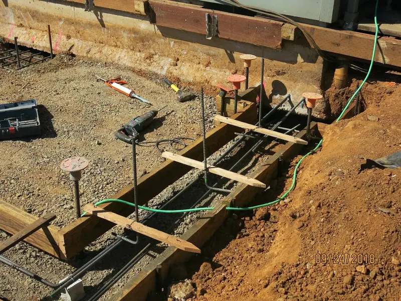 Rebar-reinforced concrete footing forms in a foundation trench during a home addition project by Red Umbrella, dated September 2018.