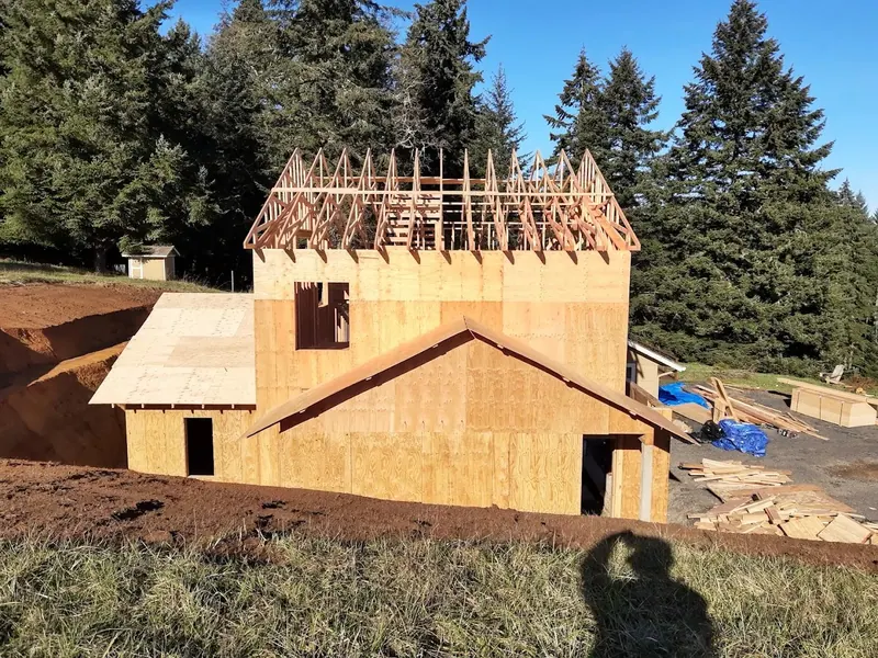 Two-story home addition framed and sheathed in OSB under blue skies, capturing Red Umbrella structural carpentry in the Pacific Northwest.