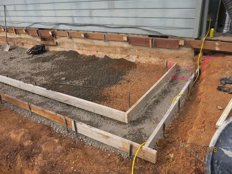 Early-stage concrete footing forms with gravel and rebar ready to pour, part of a home addition foundation project by Red Umbrella, September 2018.