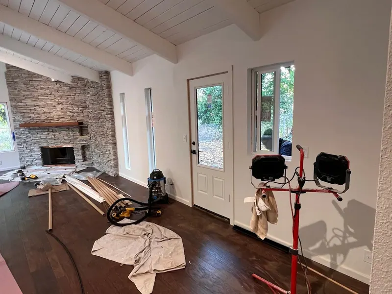 In-progress great room addition showing a newly installed exterior door and the signature stacked-stone fireplace in the background, Red Umbrella construction.