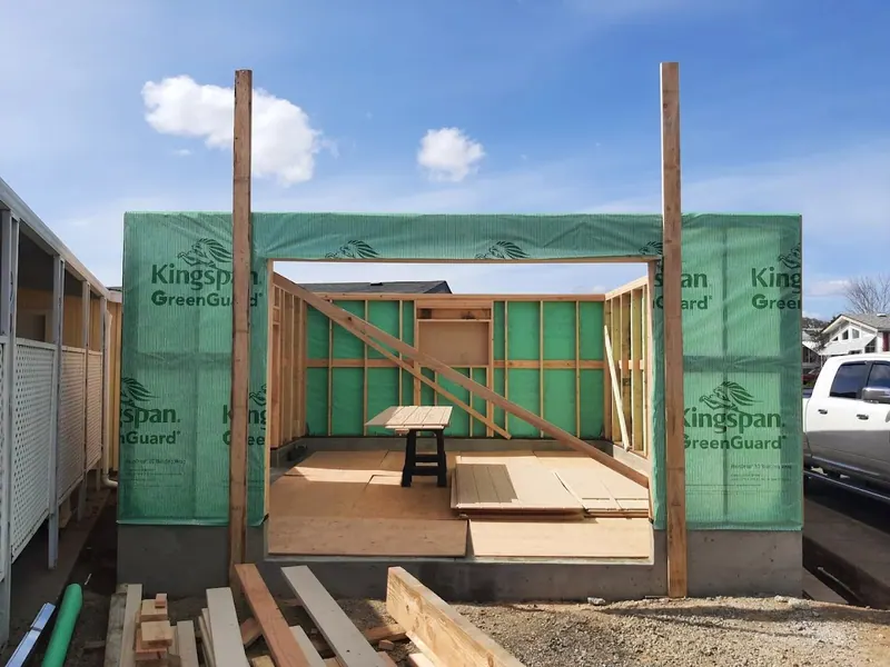 Interior view through the door opening of a new detached garage being framed with Kingspan GreenGuard building wrap on exterior walls, Red Umbrella Eugene Oregon.