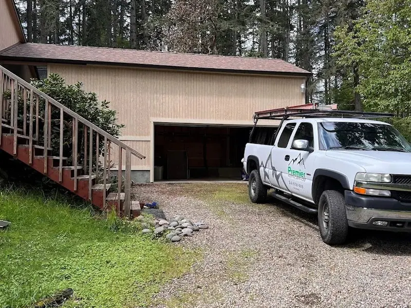 Existing detached garage in before condition with vertical board siding and gravel drive, photographed before a Red Umbrella renovation project.