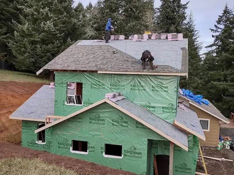 Roofing crew installing shingles on a two-story home addition wrapped in Kingspan GreenGuard, a Red Umbrella home addition project in the Pacific Northwest.