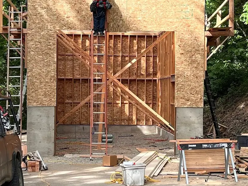 Red Umbrella carpenter standing on top of a newly framed and sheathed garage wall on a residential build near Eugene, Oregon.