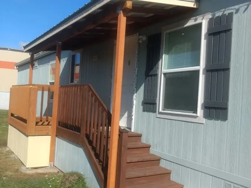 Newly built covered entry deck and stairs on a manufactured home with cedar railing and metal porch roof, a Red Umbrella outdoor project.