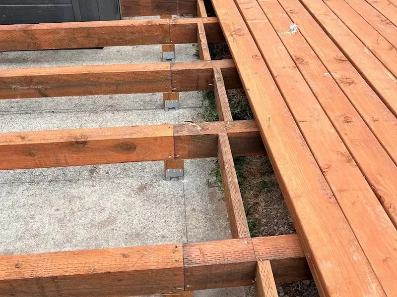 Red Umbrella crew laying cedar deck boards over a ground-level joist frame during a Eugene backyard deck build.