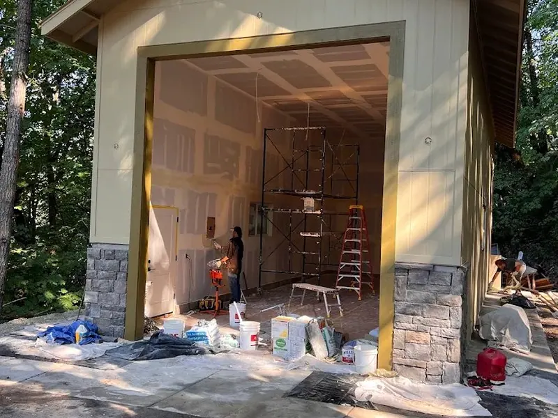 Interior finishing work underway inside a new detached garage with stone veneer base and board-and-batten siding in Eugene, Oregon.