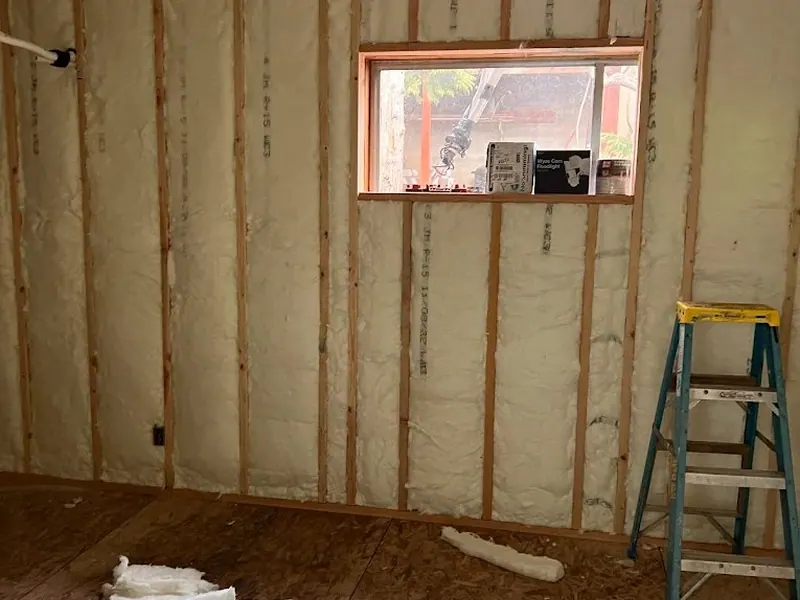 Spray foam insulation fills stud bays in a wood-framed wall during a garage conversion or ADU build by Red Umbrella in Eugene.