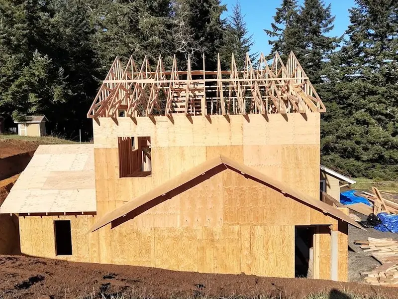 Roof trusses and two-story wall framing in progress on a new home construction project by Red Umbrella in the Eugene area.