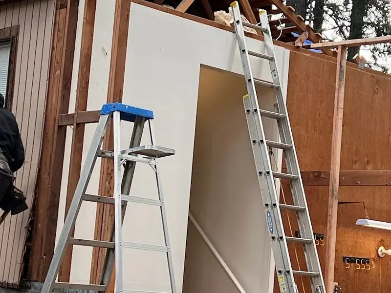 Second-story home addition framing in progress, showing new structure rising above the existing house exterior.
