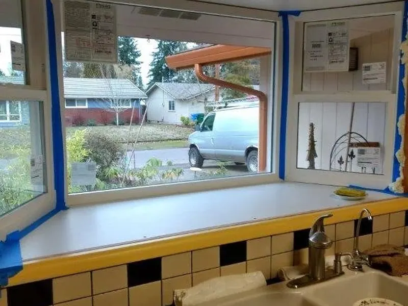 New three-panel kitchen bay window being installed above the sink, still taped for protection during a Red Umbrella kitchen renovation in Eugene, Oregon.
